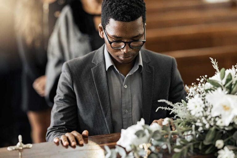 A respectful hands-on scene with two adults thoughtfully reviewing funeral planning documents at a table.