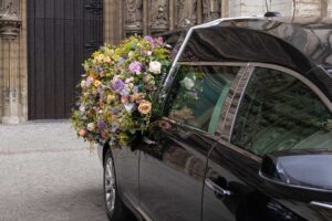 Mourners dressed in formal clothing standing together in a quiet, respectful indoor setting.