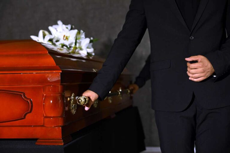 A small group of people gathered quietly around a grave, with flowers and respectful expressions.